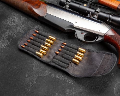 Close up photo of hunting shotgun and cartridges on dark grey background