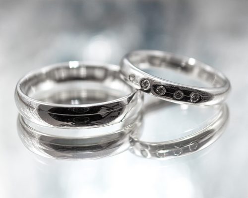 Wedding rings made of white gold with diamonds on a grey background